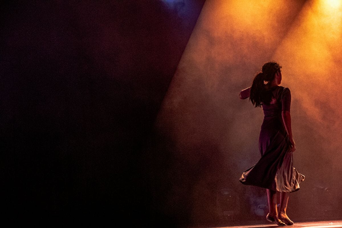 Danseuse seule en scène dans un faisceau ambre